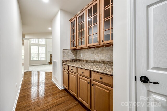 kitchen with backsplash, light stone counters, and dark wood-type flooring