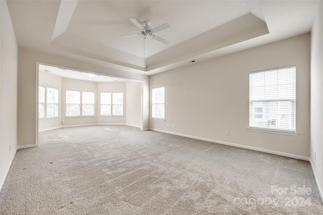 unfurnished room featuring carpet flooring, a raised ceiling, and ceiling fan