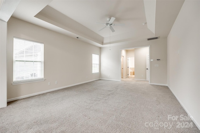 unfurnished room with light carpet, a raised ceiling, and ceiling fan