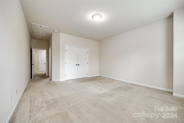 unfurnished bedroom featuring light colored carpet and a closet