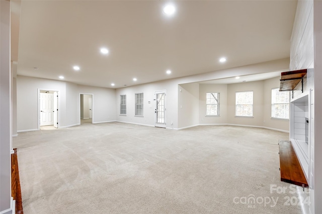 unfurnished living room with a fireplace and light carpet