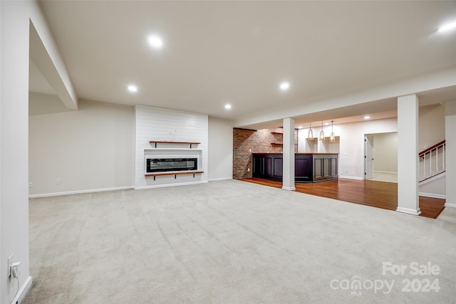 unfurnished living room featuring carpet and a brick fireplace