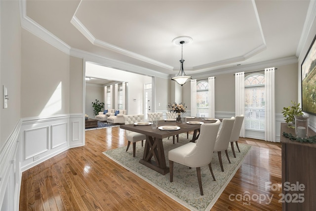 dining room featuring a raised ceiling, crown molding, and hardwood / wood-style floors