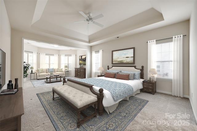 bedroom with carpet floors, ceiling fan, and a tray ceiling