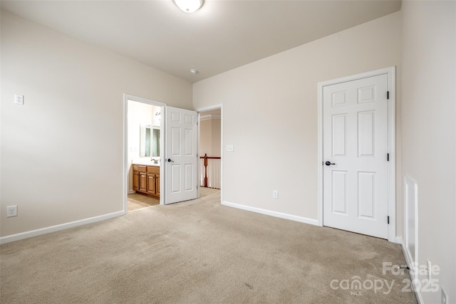 unfurnished bedroom with ensuite bathroom and light carpet