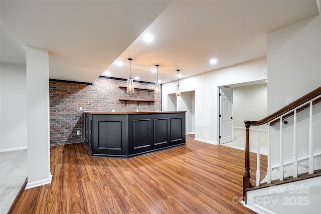 bar featuring hardwood / wood-style floors, decorative light fixtures, and brick wall