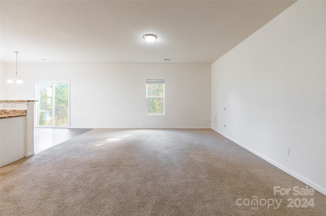 unfurnished room featuring carpet flooring and a notable chandelier