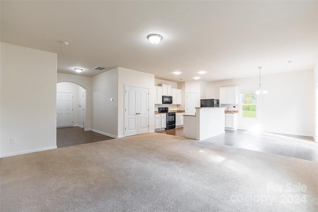 unfurnished living room featuring dark carpet and an inviting chandelier