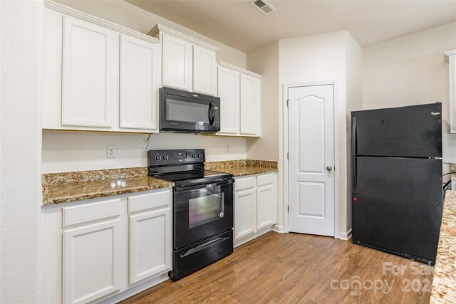 kitchen with dark stone counters, white cabinetry, light hardwood / wood-style flooring, and black appliances