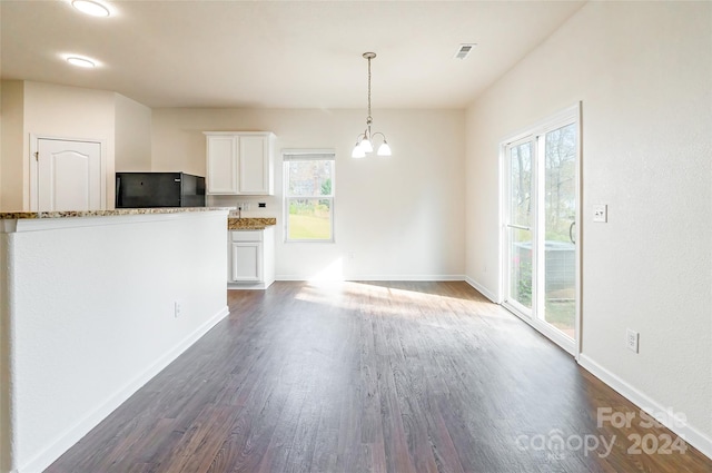 interior space featuring black fridge, pendant lighting, stone countertops, white cabinets, and dark hardwood / wood-style floors