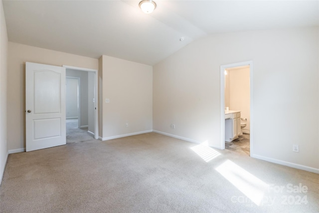 unfurnished bedroom featuring light carpet, connected bathroom, and vaulted ceiling