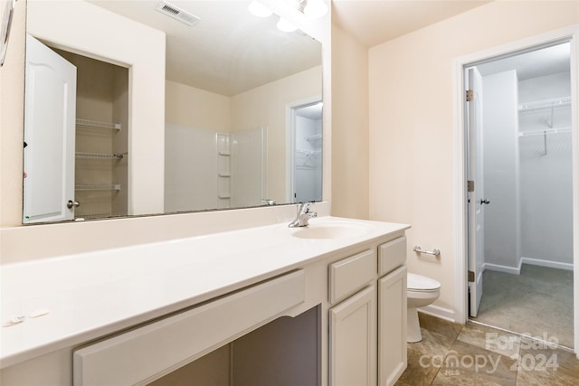 bathroom with tile patterned floors, a shower, vanity, and toilet