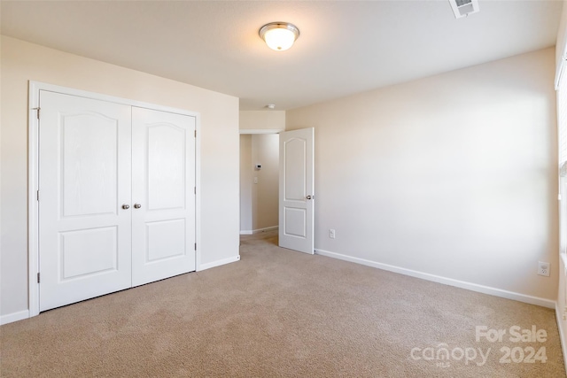 unfurnished bedroom featuring light colored carpet and a closet