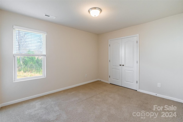 unfurnished bedroom featuring light colored carpet and a closet