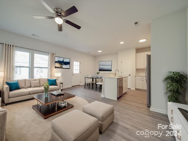 living room with ceiling fan, light hardwood / wood-style floors, and sink