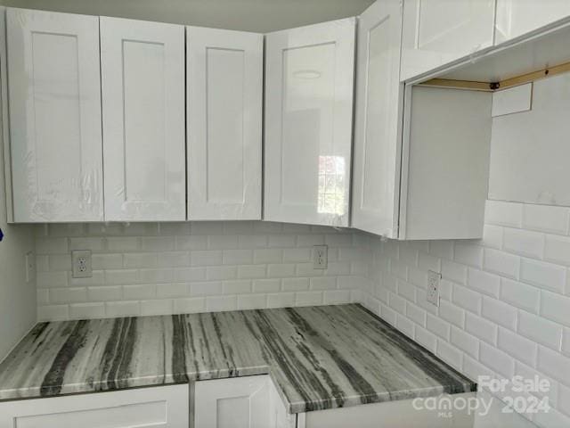 details featuring white cabinets and decorative backsplash