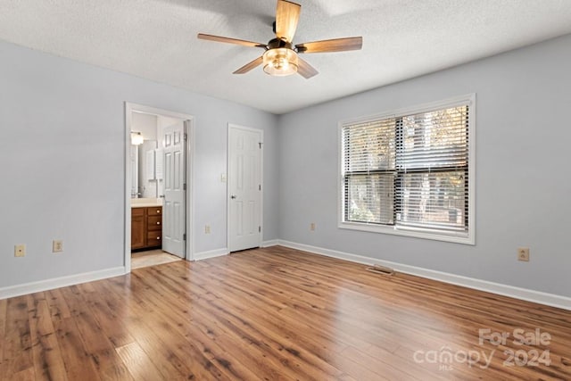 unfurnished bedroom with ensuite bathroom, ceiling fan, a textured ceiling, and light wood-type flooring