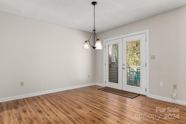 interior space featuring a chandelier, french doors, wood-type flooring, and a textured ceiling