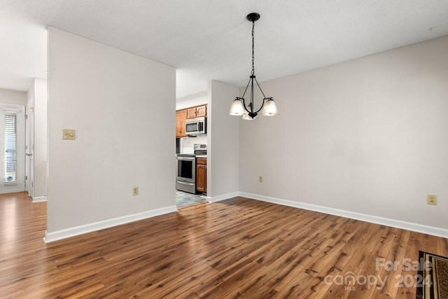 unfurnished dining area with hardwood / wood-style floors and a notable chandelier