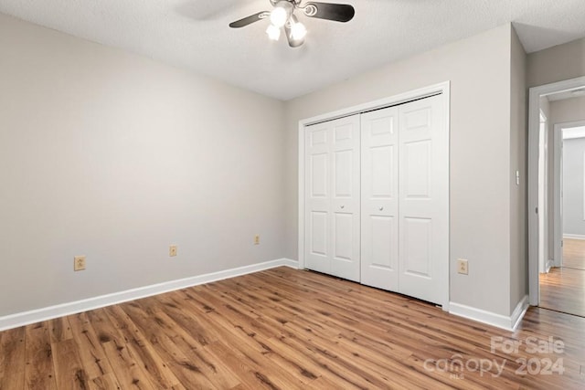 unfurnished bedroom with a textured ceiling, light wood-type flooring, a closet, and ceiling fan