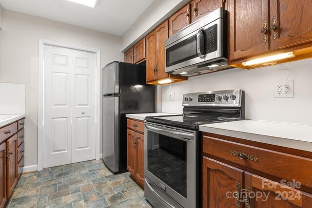 924 Cranberry Cir Unit 50-C, Fort Mill, SC 29715 - kitchen featuring appliances with stainless steel finishes, stone finish flooring, light countertops, and brown cabinetry