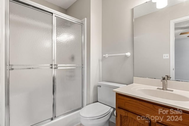 bathroom featuring a shower with door, vanity, and toilet