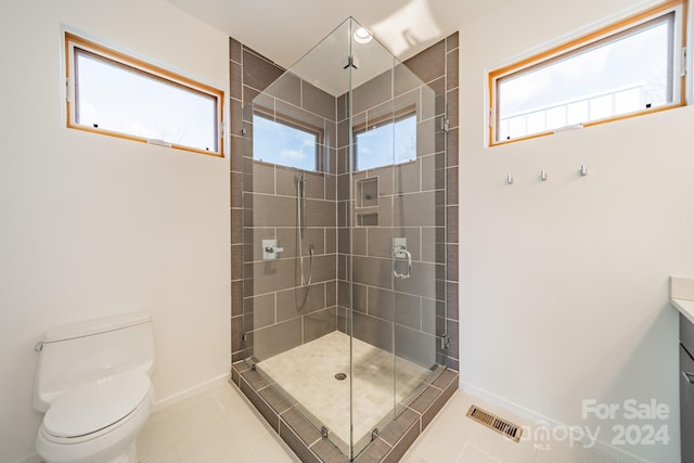 bathroom featuring tile patterned flooring, vanity, toilet, and a shower with shower door