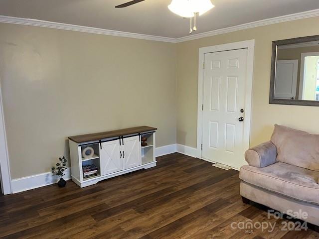 sitting room featuring ceiling fan, crown molding, and dark wood-type flooring