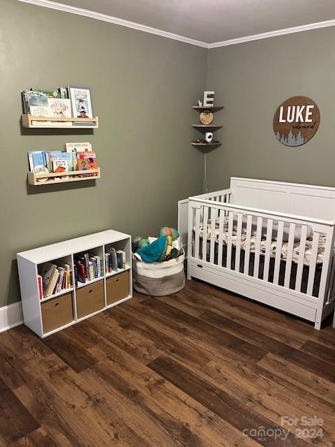 bedroom with dark hardwood / wood-style floors, a crib, and crown molding