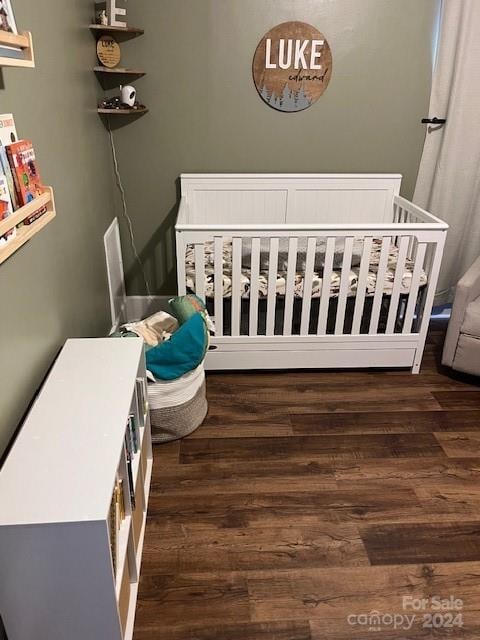 bedroom featuring dark hardwood / wood-style floors and a crib