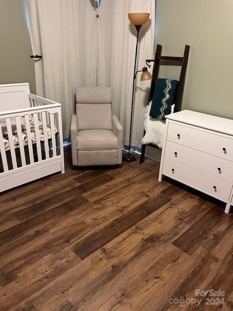 bedroom featuring dark wood-type flooring and a crib