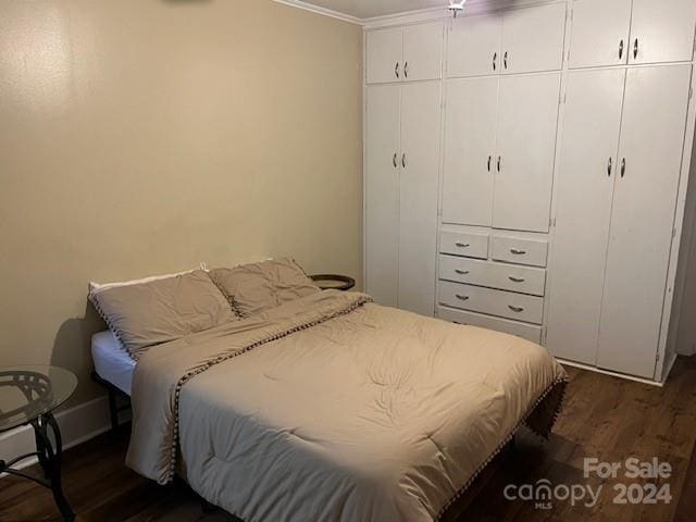 bedroom with dark hardwood / wood-style flooring and crown molding