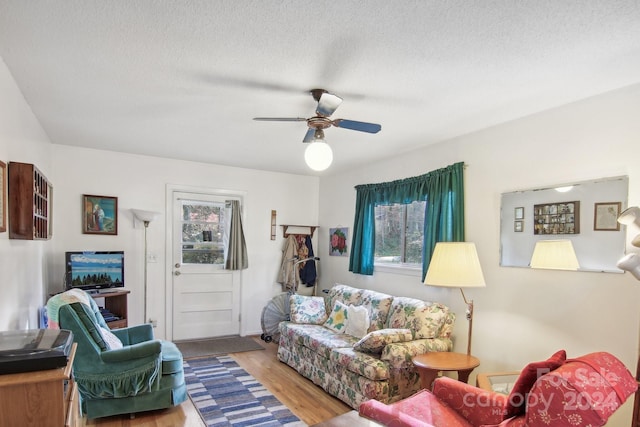 living room featuring hardwood / wood-style flooring, ceiling fan, and a textured ceiling