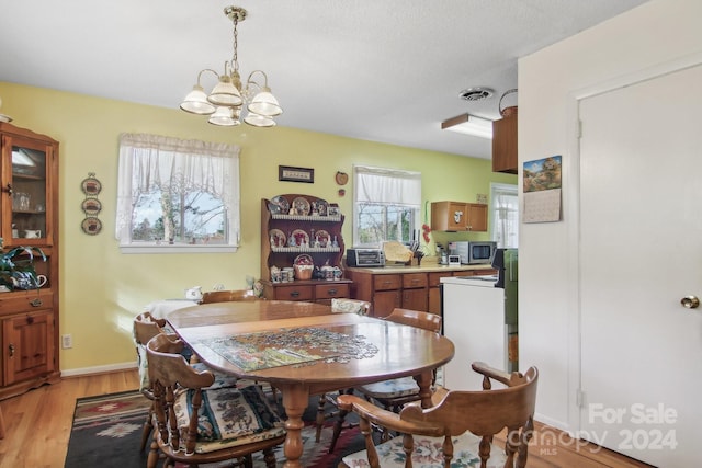 dining room featuring a chandelier, a textured ceiling, and light hardwood / wood-style floors