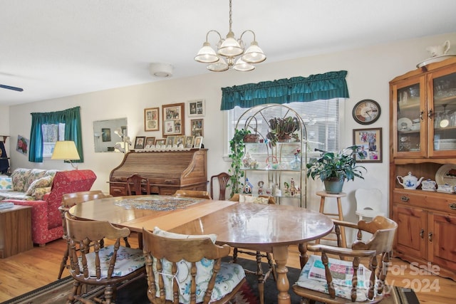 dining space with ceiling fan with notable chandelier and light hardwood / wood-style flooring