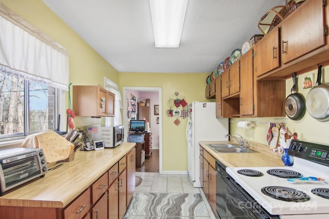 kitchen featuring sink, light tile patterned floors, stainless steel appliances, and a textured ceiling