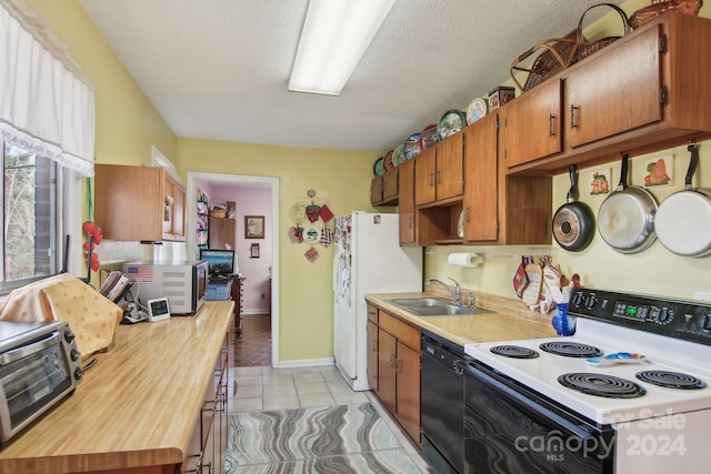 kitchen with a textured ceiling, white appliances, sink, and light tile patterned floors