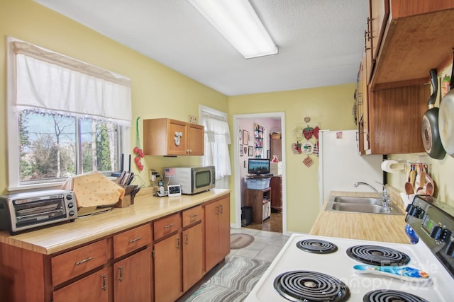 kitchen with sink, light tile patterned floors, white electric range oven, and a textured ceiling