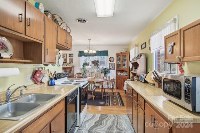 kitchen featuring sink, white range with electric cooktop, pendant lighting, a chandelier, and light hardwood / wood-style floors