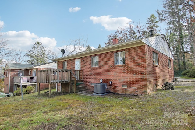 rear view of house with central AC unit, a lawn, and a wooden deck