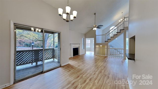 unfurnished living room featuring ceiling fan with notable chandelier, light wood-type flooring, and high vaulted ceiling