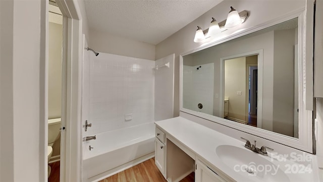 full bathroom featuring vanity, a textured ceiling, wood-type flooring, shower / bathing tub combination, and toilet