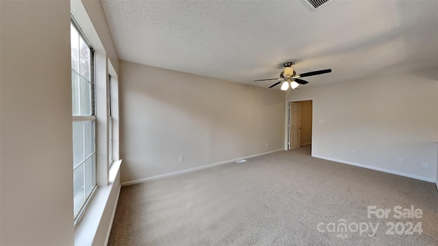 carpeted spare room featuring ceiling fan and a textured ceiling