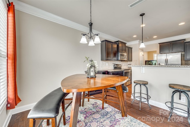 dining area with a chandelier, crown molding, and dark wood-type flooring