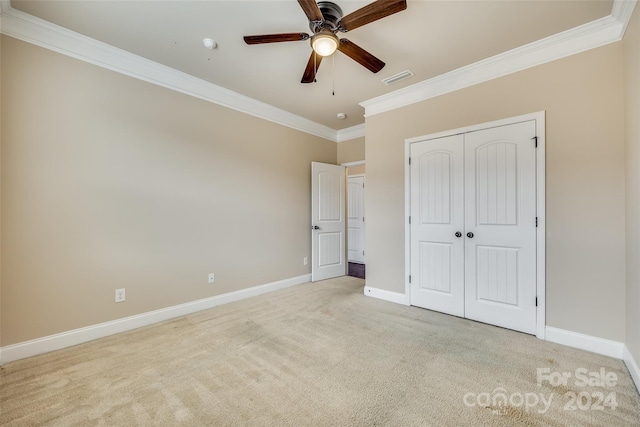 unfurnished bedroom with ceiling fan, light colored carpet, crown molding, and a closet