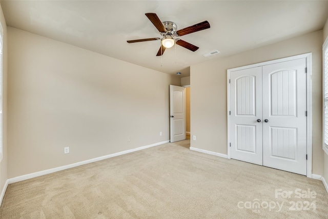 unfurnished bedroom with ceiling fan, light colored carpet, and a closet