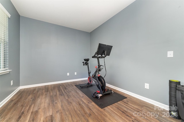 exercise room with dark hardwood / wood-style floors and lofted ceiling