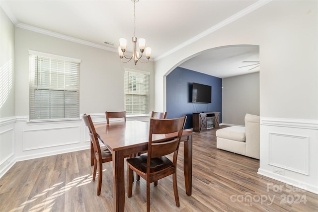 dining space with ornamental molding, ceiling fan with notable chandelier, and hardwood / wood-style flooring