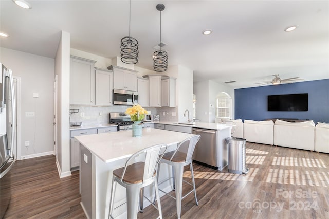 kitchen with stainless steel appliances, ceiling fan, dark wood-type flooring, sink, and hanging light fixtures