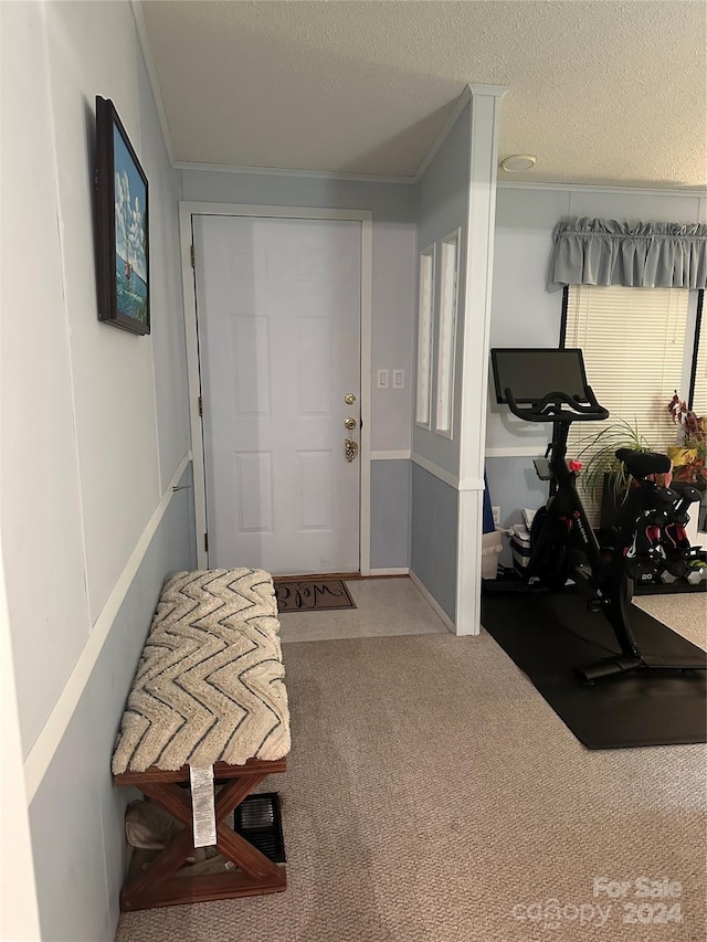 entrance foyer with carpet, a textured ceiling, and ornamental molding